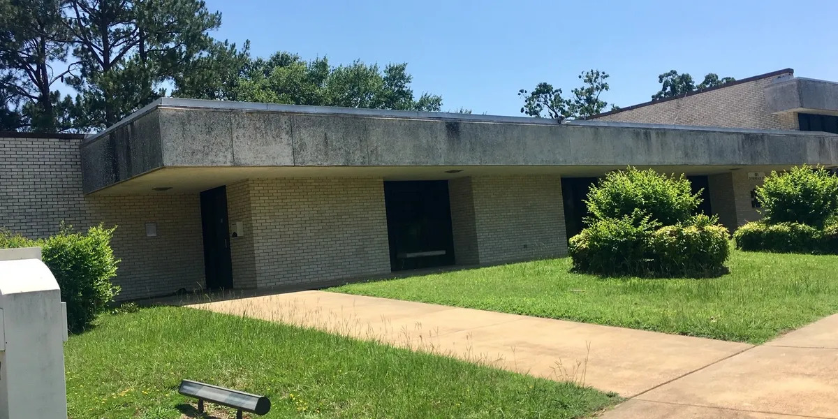 picture of office with bright green grass and bushes in front